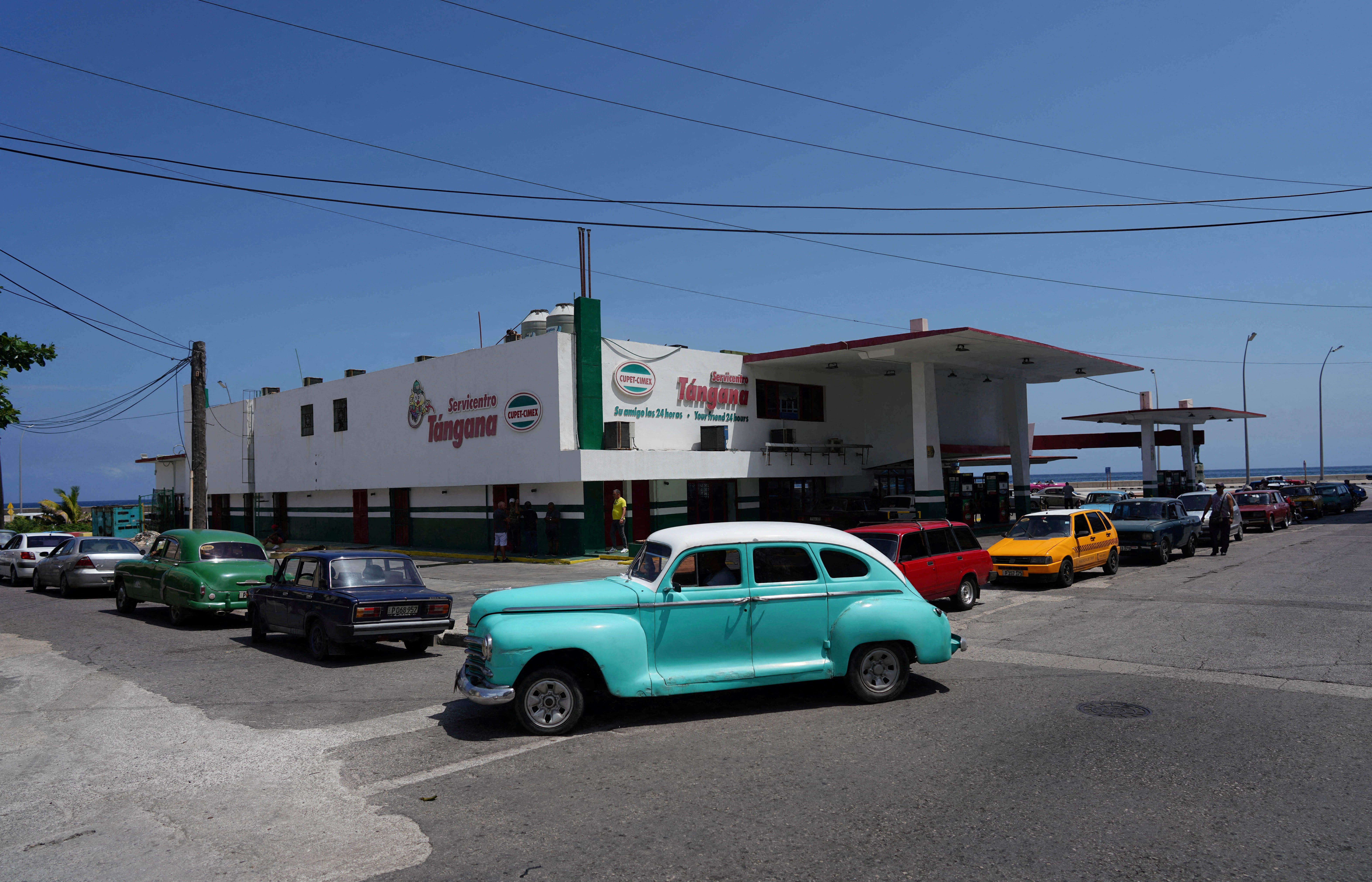 Pessoas aguardam volta da eletricidade para abastecer seus carros em posto de combustível de Havana