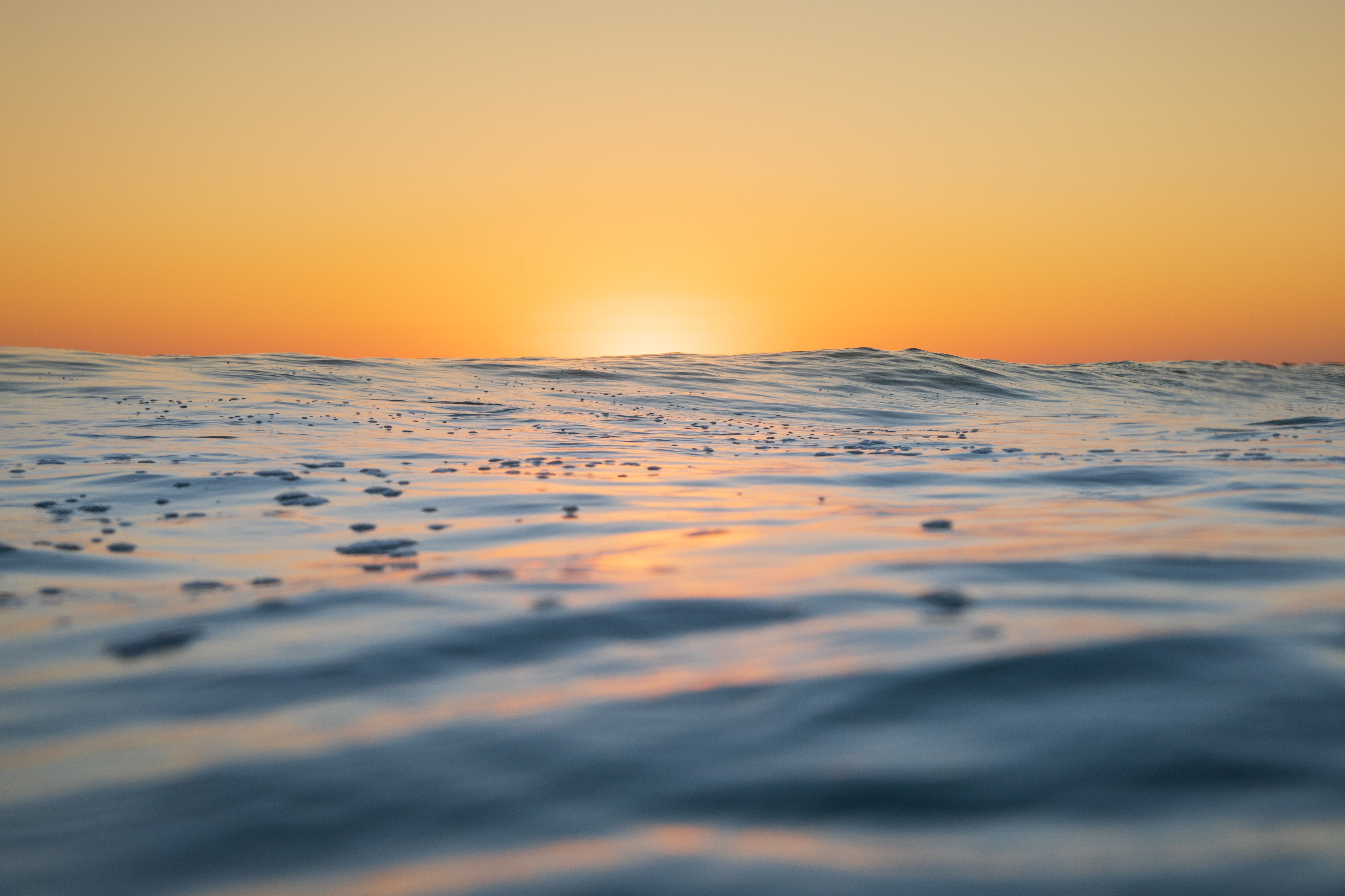 Close up of the ocean surface as the sun starts to rise and  colour it golden.
