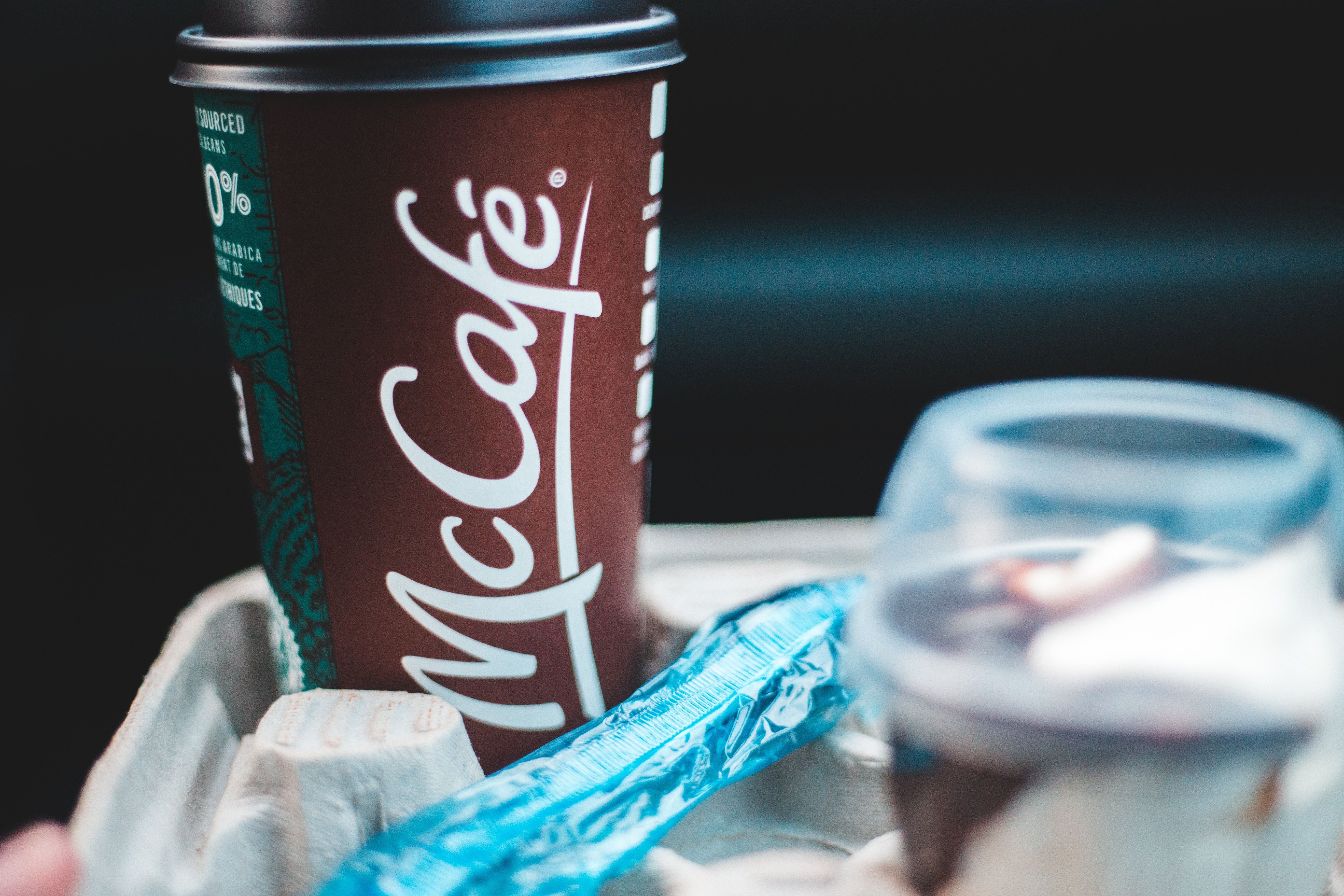 Copo de café antigo do McDonald's. Ele é marrom e nele se lê "McCafé"
