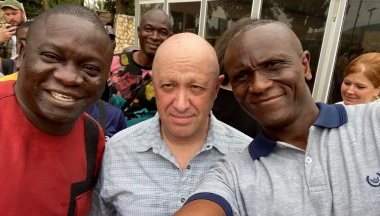 Anfisa Alexandrovna Kiryanova (à direita) aparece no fundo de uma foto de Prigozhin do lado de fora da Casa Russa no mês passado / All Eyes on Wagner/Twitter