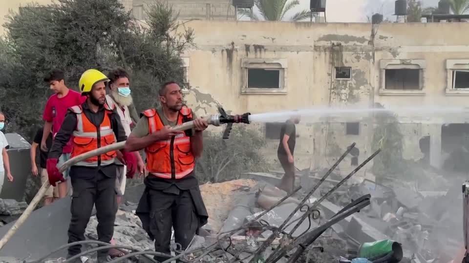 Cidadãos de Gaza e membros da Defesa Civil apagam fogo em casa atingida por ataque aéreo israelense
