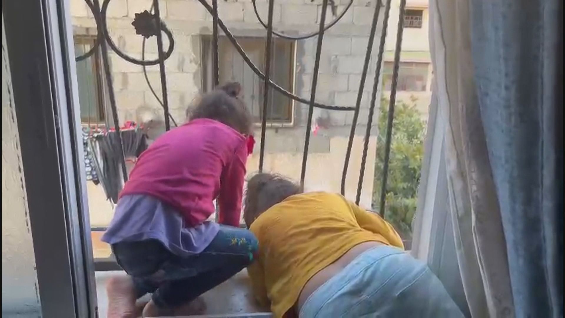 Pela janela, crianças observam destruição em Gaza
