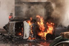 Pessoas tentam apagar fogo em carros após um ataques de mísseis vindos de Gaza no sábado (7)