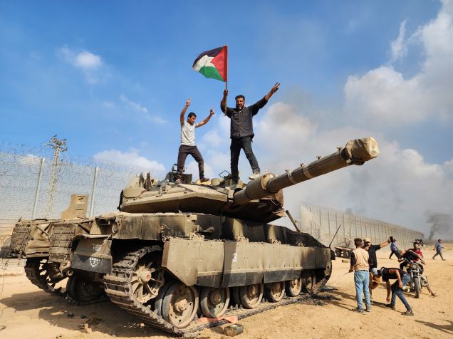 Braço armado do Hamas, Brigadas Izz ad-Din al-Qassam seguram bandeira palestina enquanto destroem tanque das forças israelenses na Cidade de Gaza em 7 de outubro / Foto de Hani Alshaer/Anadolu Agency via Getty Images