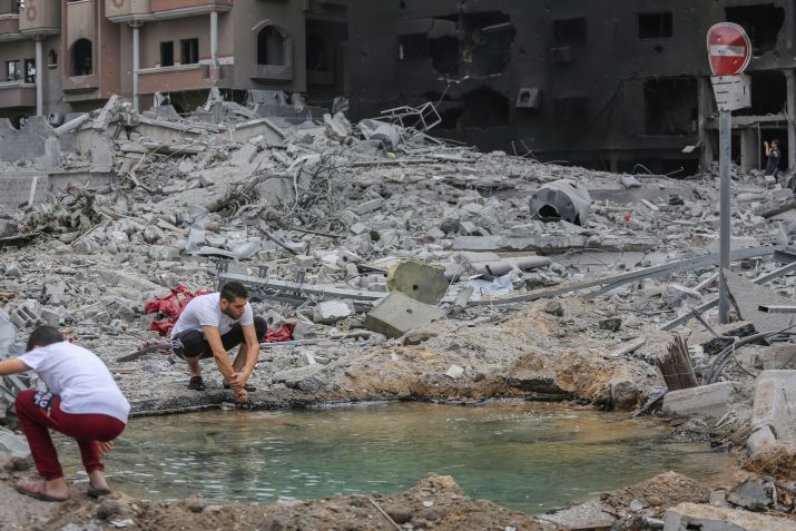 Homem palestino lava as mãos em uma poça ao lado de um prédio destruído após os ataques israelenses na Cidade de Gaza / Ahmed Zakot/SOPA Images/LightRocket via Getty Images