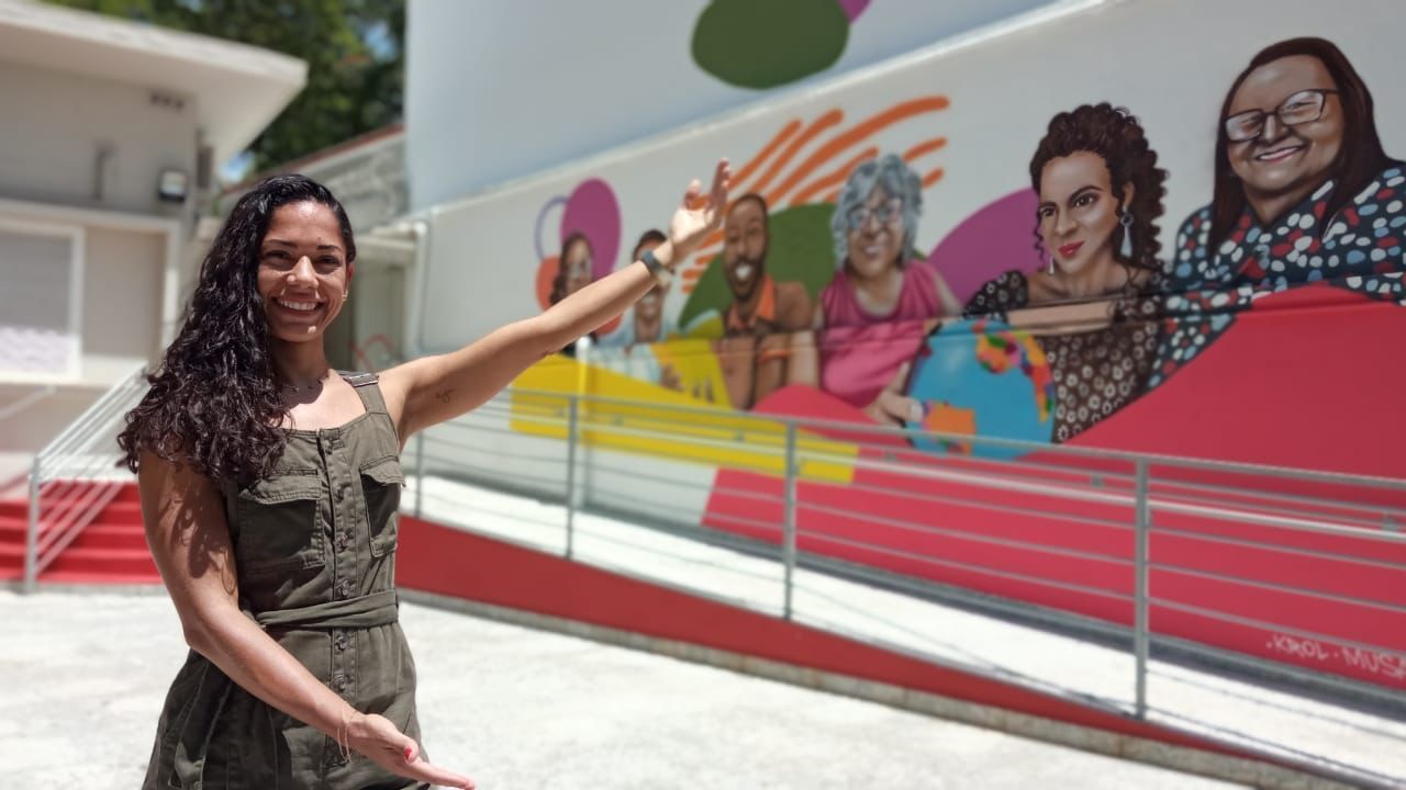 A grafiteira Musa posa ao lado do painel que fez em homenagem aos professores / Claudio Yoshinaga/Divulgação