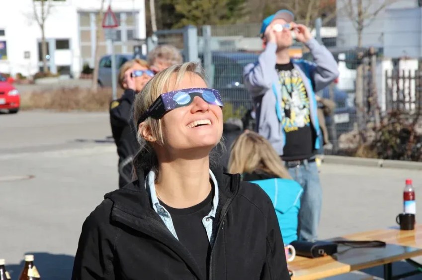 Mulher usa óculos com proteção especial para observação de eclipses solares / Divulgação/Alpine Astronomical