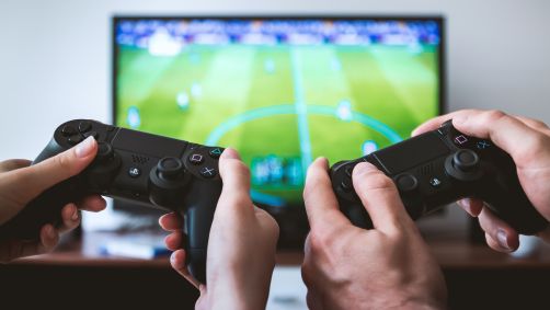 Duas pessoas segurando controles e jogando videogame