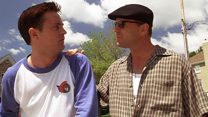 Perry (à esq.) com camisa do Senators em cena com Bruce Willis / Reprodução