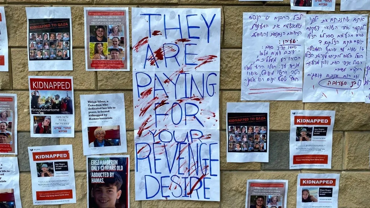 Fotos de pessoas que foram sequestradas pelo Hamas são exibidas em uma parede ao lado de slogans de protesto em Tel Aviv em 14 de outubro de 2023 / Ivana Kottasová/CNN