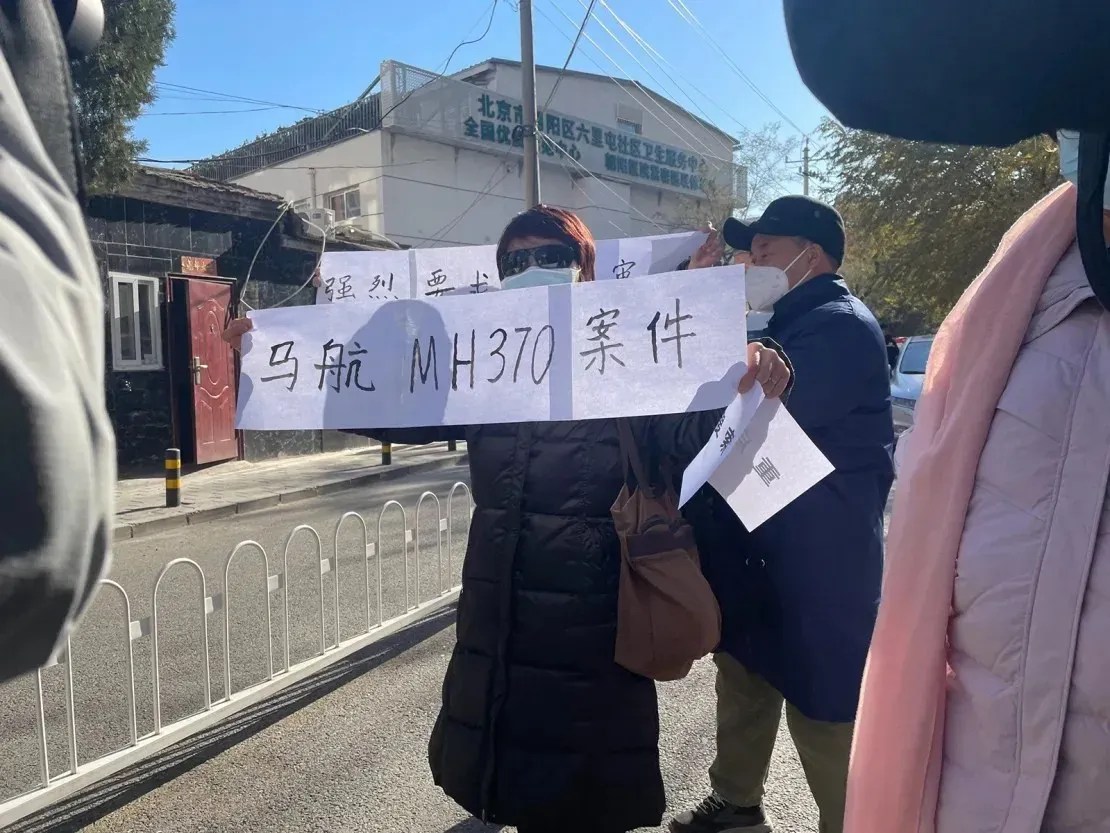 Familiares de passageiros a bordo do voo MH370 seguram cartazes exigindo julgamento aberto perto de um tribunal no distrito de Chaoyang, em Pequim, durante uma audiência a portas fechadas em 27 de novembro de 2023 / Reprodução/CNN