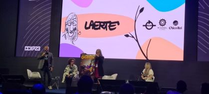 Laerte Coutinho em painel da CCXP23 Unlock, segurando um poster do filme "Overman"