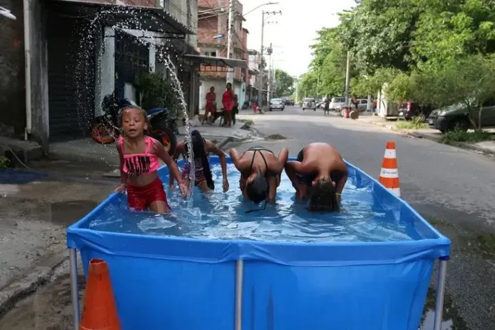 Moradores do Complexo da Maré se refrescam com chuveiros e piscinas improvisadas nas ruas da comunidade. Sensação térmica no Rio de Janeiro voltou a superar os 50 °C / Tânia Rêgo/Agência Brasil