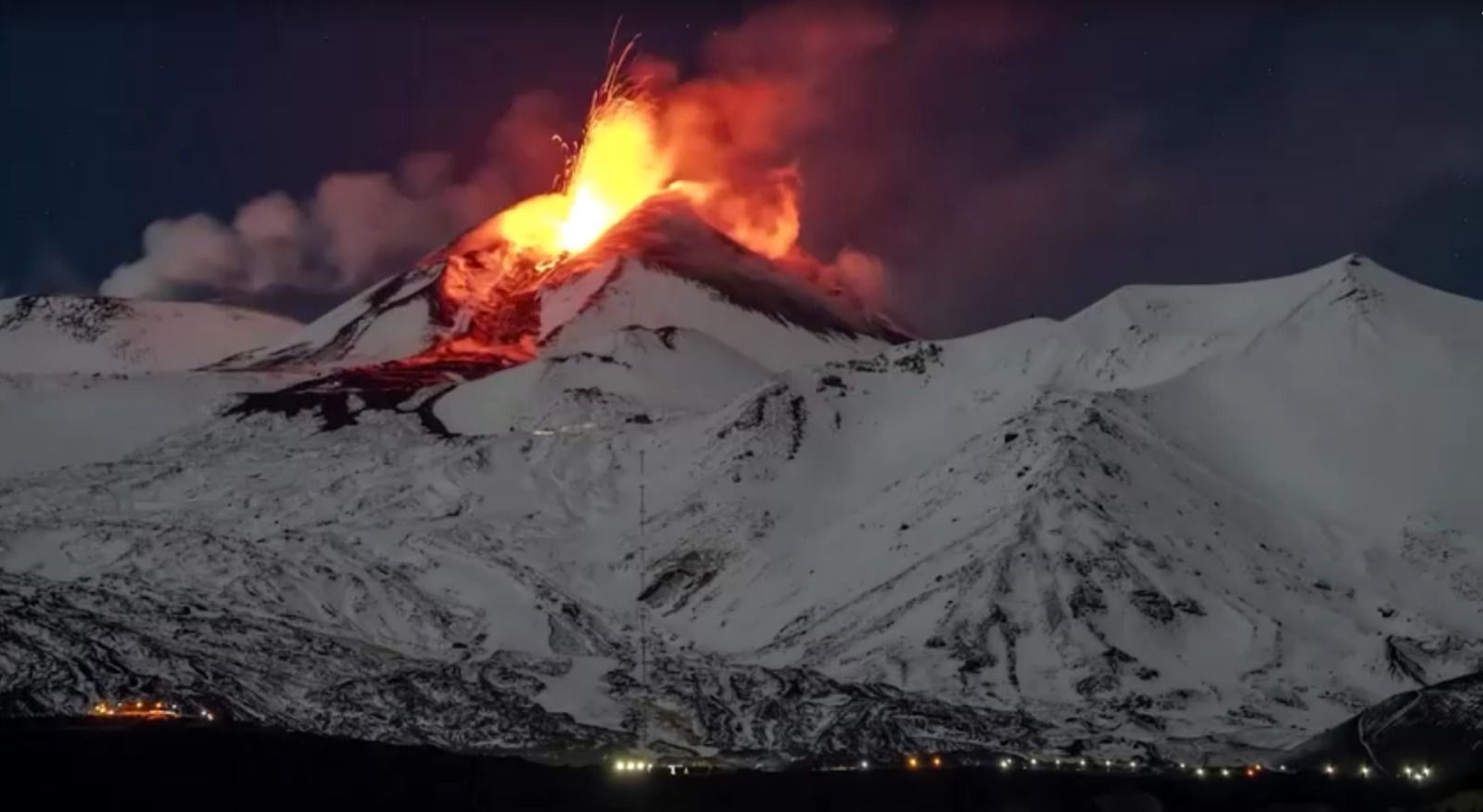 O Monte Etna coberto de neve jorra lava no céu noturno