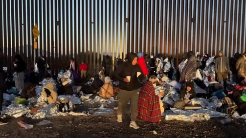 Migrantes aguardando transporte da Patrulha de Fronteira na cerca da fronteira entre Estados Unidos e México no dia de Natal