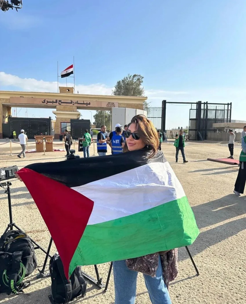 Mirna El Helbawi na passagem de fronteira de Rafah, entre Gaza e Egito, com uma bandeira palestina pendurada nas costas / Mirna El Helbawi/Arquivo Pessoal