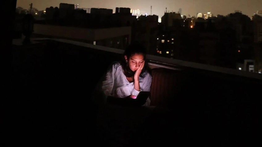 Mirna El Helbawi está no Cairo, Egito, usando o seu telefone para coordenar a distribuição de chips de celular virtuais em Gaza / Pola Salem