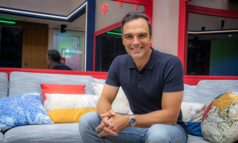 Tadeu Schmidt sentado na sala da casa do BBB23