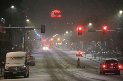 Pessoa passeia com cachorros em rua coberta por neve em Des Moines, Iowa, nos EUA