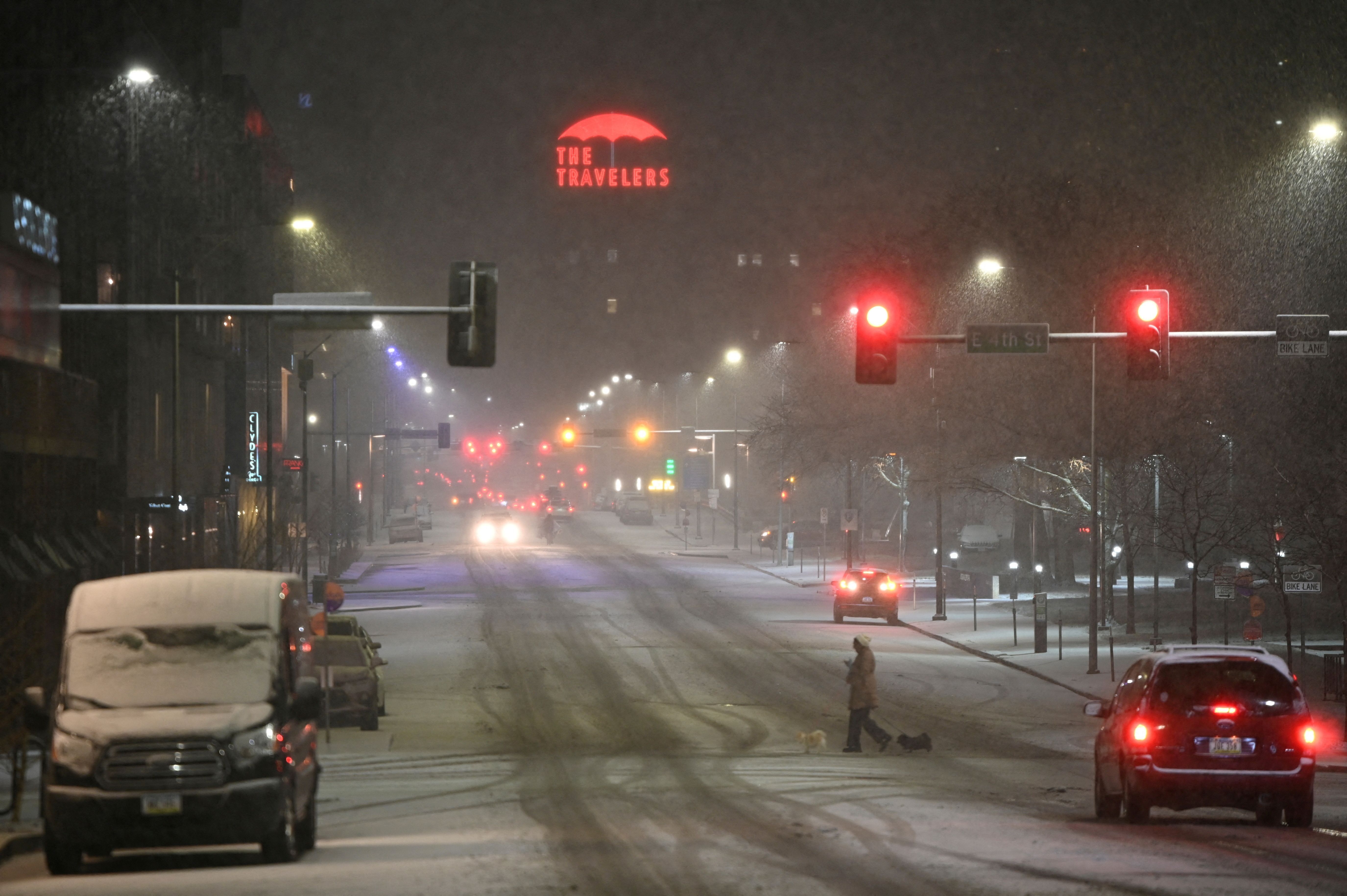 Pessoa passeia com cachorros em rua coberta por neve em Des Moines, Iowa, nos EUA
