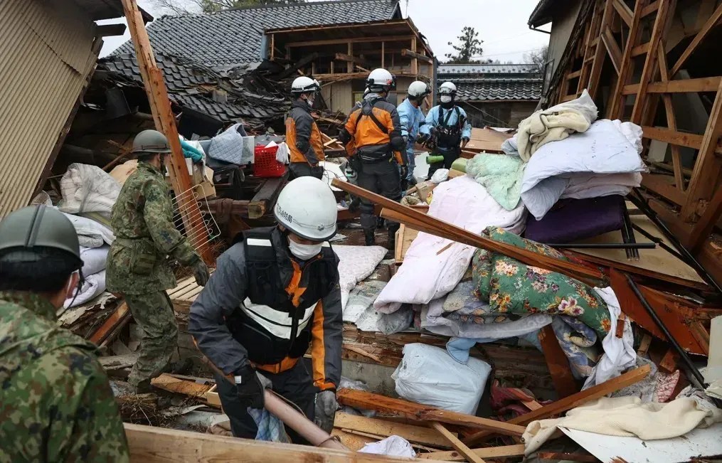 Bombeiros e membros da Força de Autodefesa do Japão resgatam um homem idoso de uma casa desabada em 3 de janeiro de 2024 em Suzu, Ishikawa, Japão. / The Asahi Shimbun/Getty Images