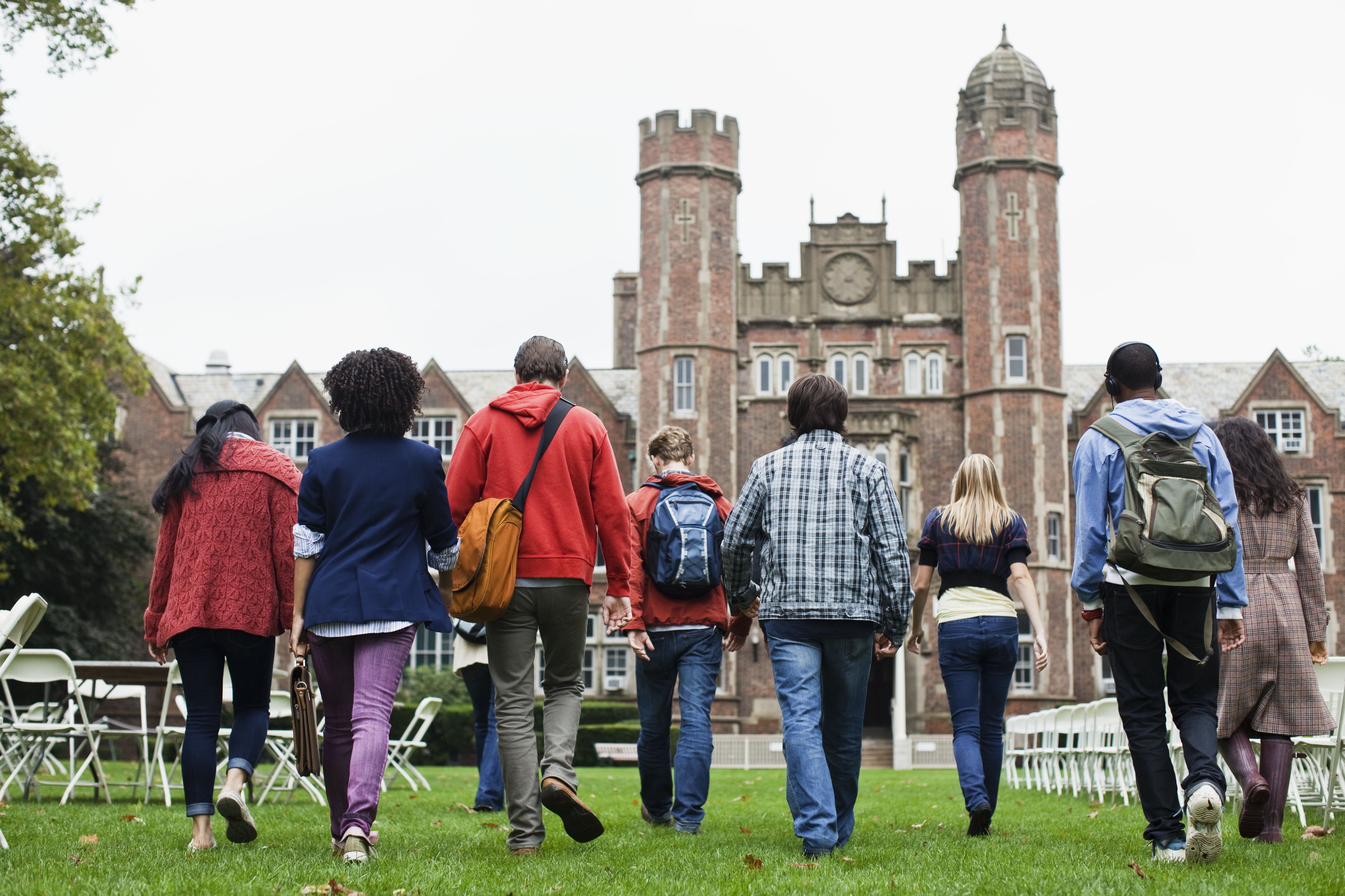 Estudantes caminham em campus de universidade.