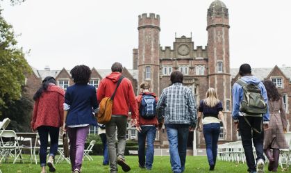 Estudantes caminham em campus de universidade.