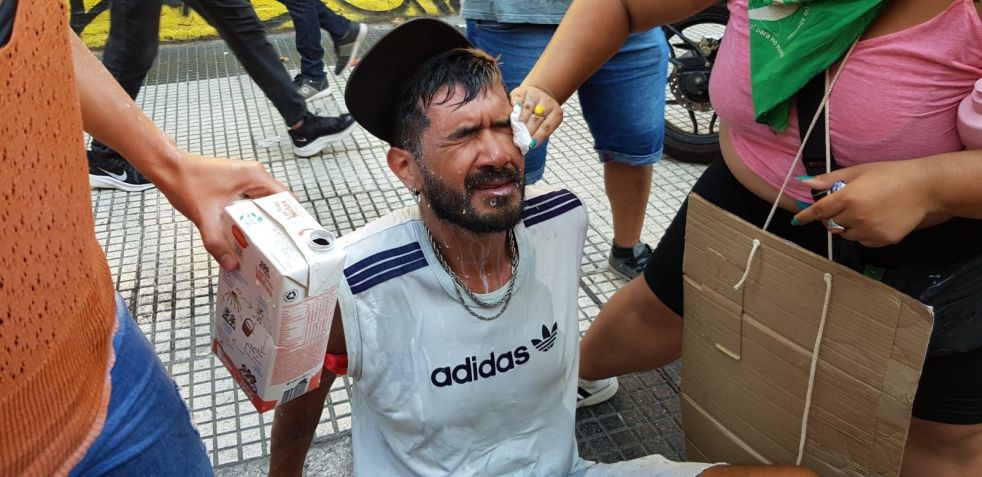 Manifestantes ajudam homem que não conseguia abrir os olhos após ser atingido por gás de pimenta durante protesto contra megaprojeto de Javier Milei / Luciana Taddeo/CNN