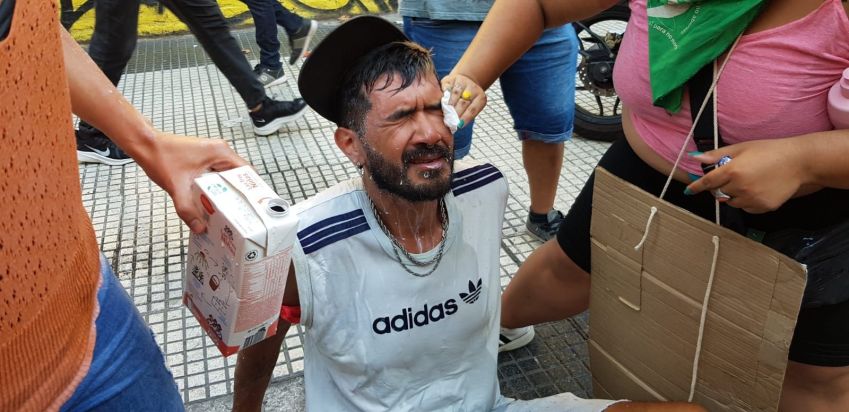 Manifestantes ajudam homem que não conseguia abrir os olhos após ser atingido por gás de pimenta durante protesto contra megaprojeto de Javier Milei / Luciana Taddeo/CNN