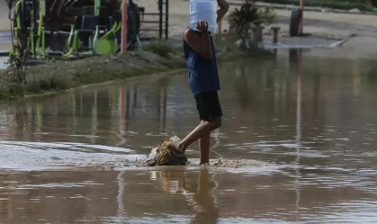 Homem anda em rua alagada