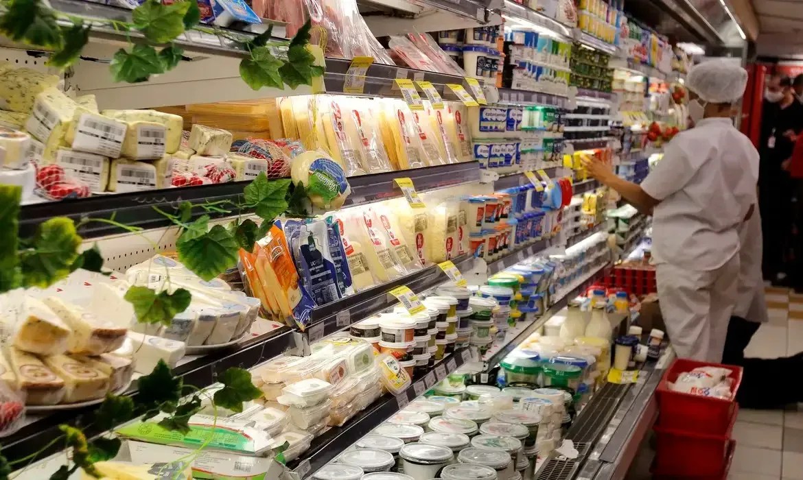 Funcionários de supermercado organizam itens em geladeira de laticínios