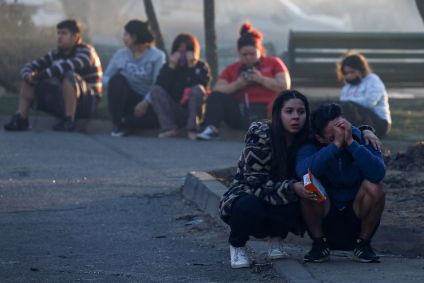 Pessoas se consolam após perderem sua casa em consequência de um incêndio florestal que deixou milhares de casas destruídas nas colinas de Vina del Mar, Chile, em 3 de fevereiro de 2024.