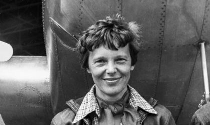 pilota Amelia Earhart em frente ao seu avião em uma foto preto e branca