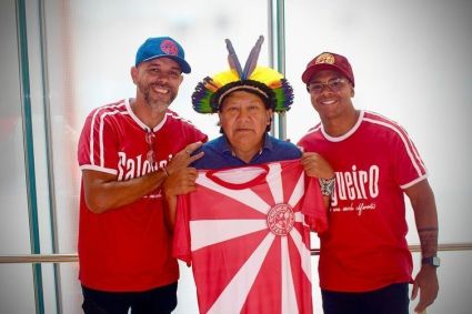 Carnavalesco Edson Pereira com o enredista Igor Pereira e o xamã Yanomami Davi Kopenawa em uma foto com a bandeira da Salgueiro
