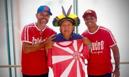 Carnavalesco Edson Pereira com o enredista Igor Pereira e o xamã Yanomami Davi Kopenawa em uma foto com a bandeira da Salgueiro
