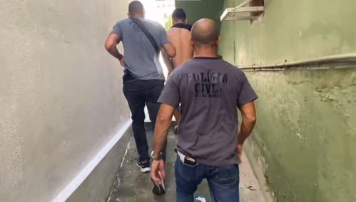 Dois policiais civis acompanham o criminoso José Roberto Muniz de Sousa, o Ret, que está sem camisa