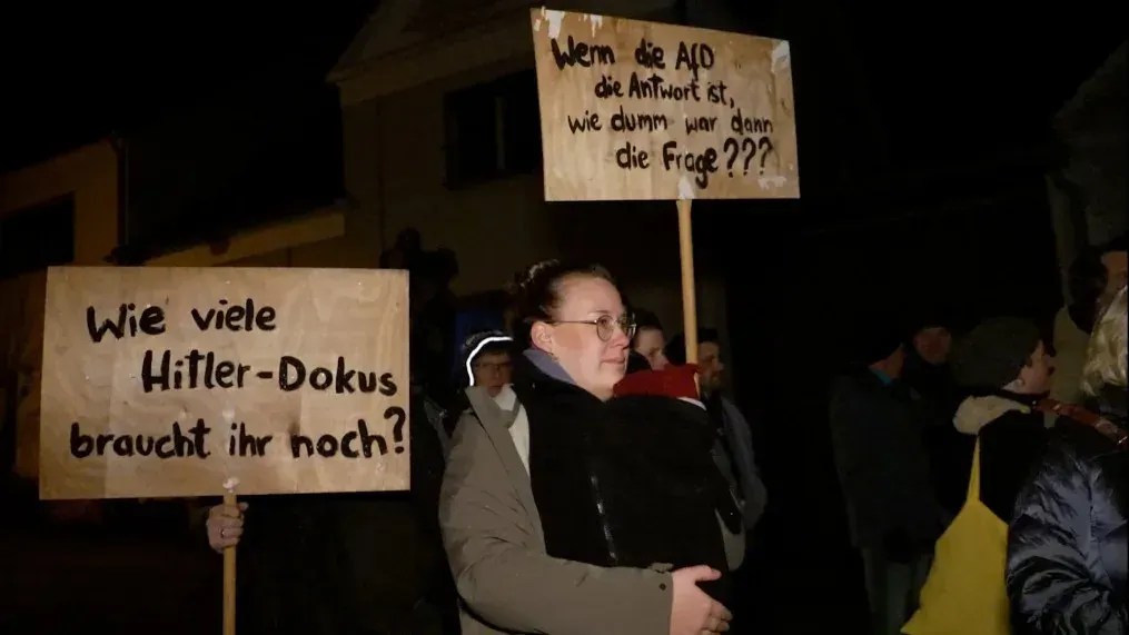 Manifestantes contra a AfD manifestam-se no caminho da reunião. As placas dizem: 'Quantos mais documentários sobre Hitler você precisa?' E: 'Se a AfD é a resposta, então quão estúpida foi a pergunta?' / Chris Stern/CNN