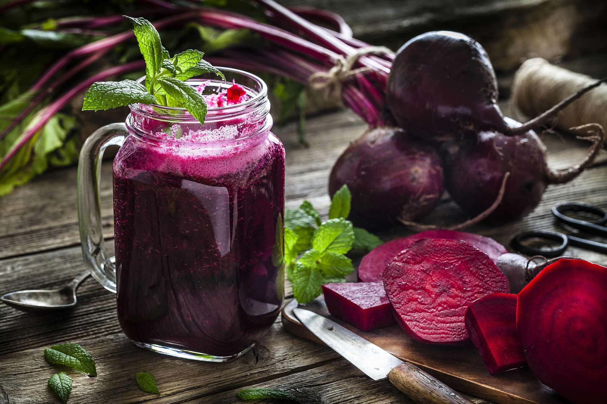 Suco de beterraba servido em copo de vidro, em uma mesa, ao lado de pedaços de beterraba
