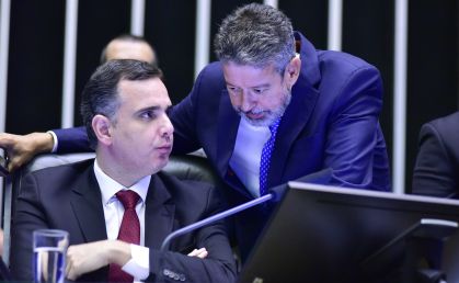 Arthur Lira, de pé e inclinado para baixo, conversa com Rodrigo Pacheco, que está sentado