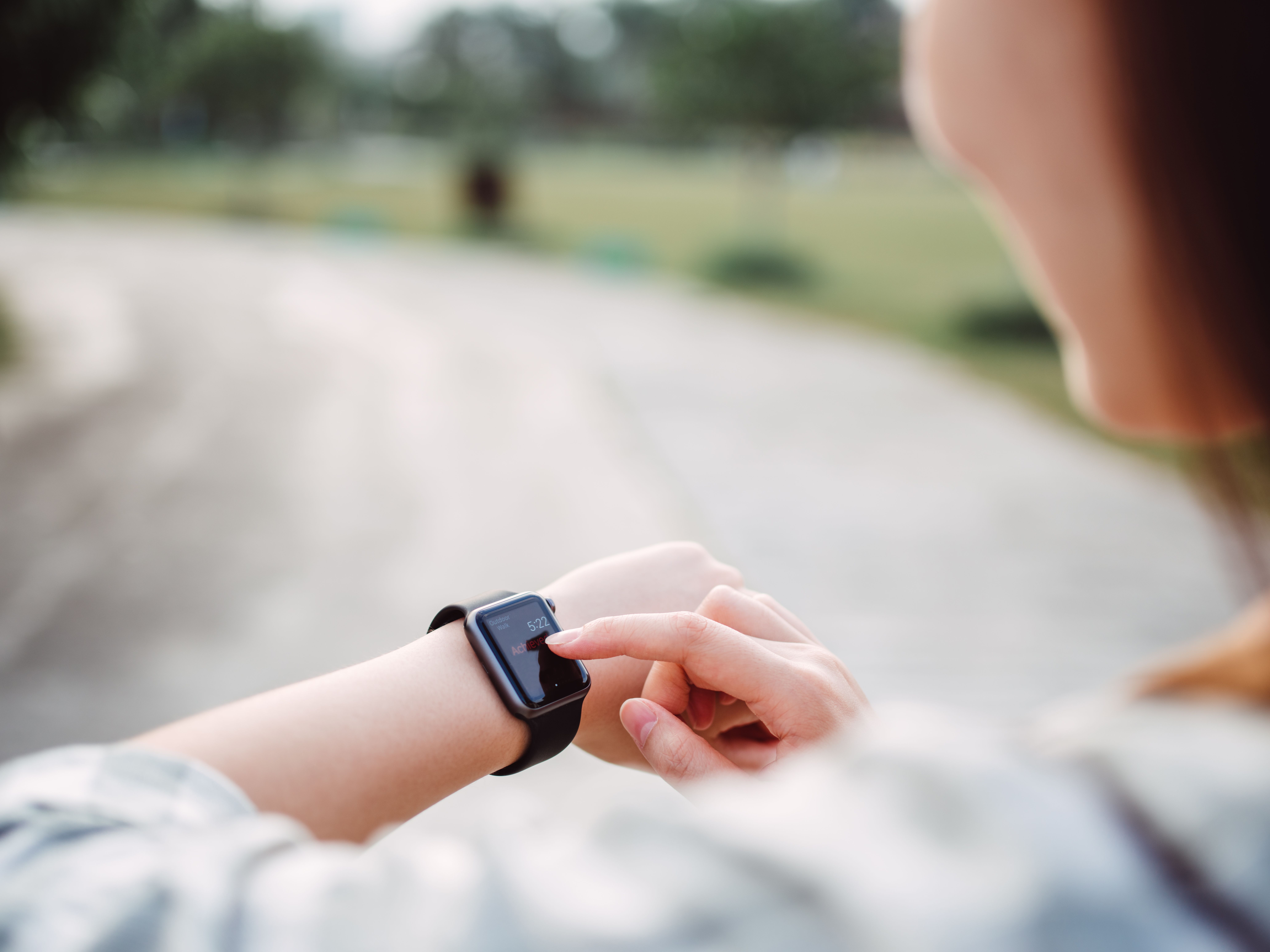 Pretty young lady using smart watch in the pathway