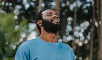Homem respirando ar puro em um parque repleto de árvores