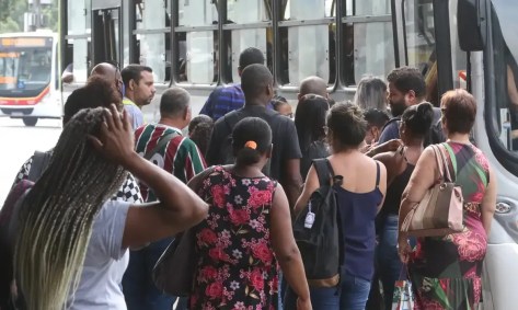 Pessoas enfileiradas para entrar no transporte público