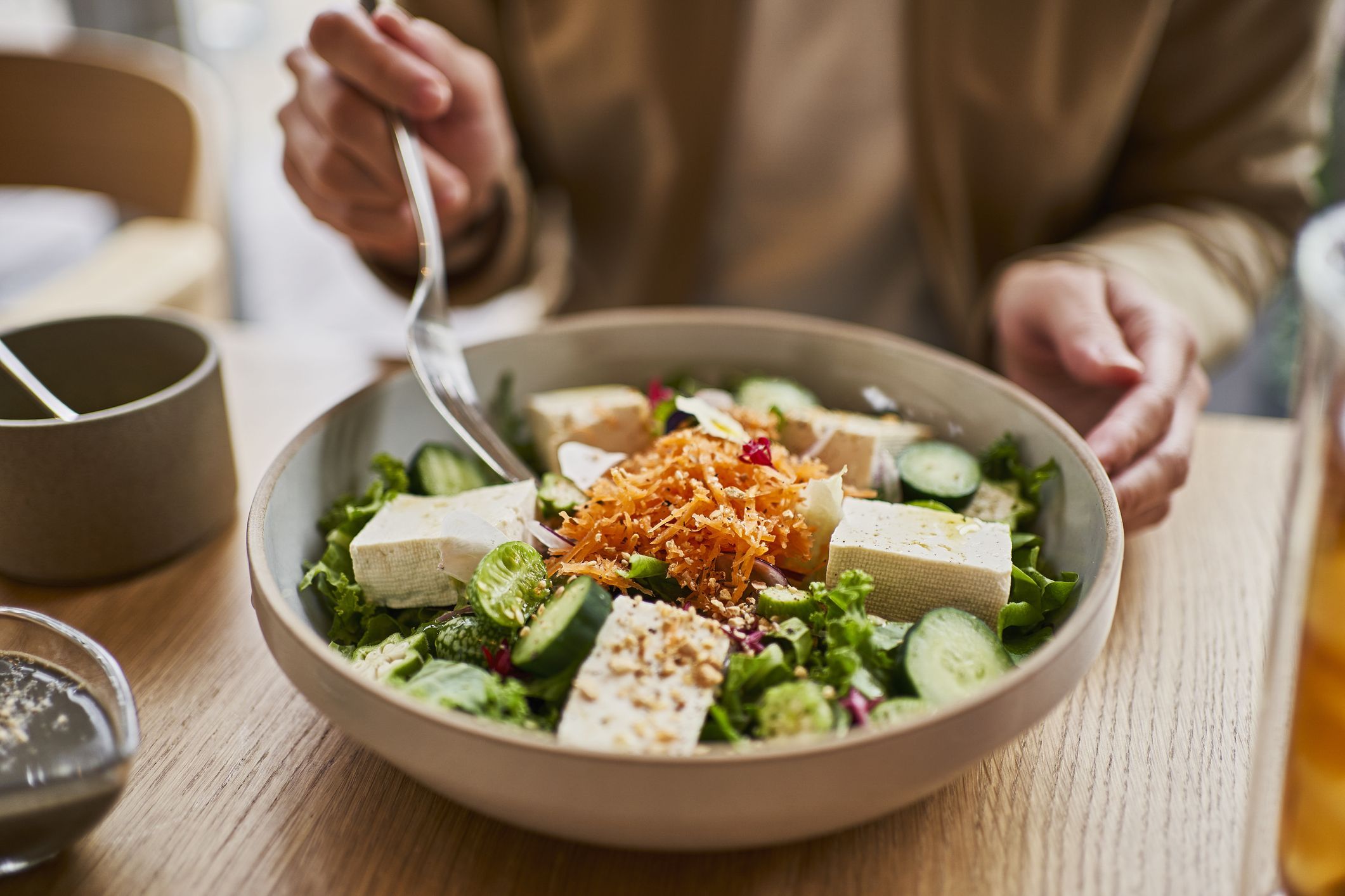 Mulher comendo salada com tofu