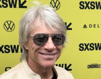 O cantor bon jovi posando para foto no backdrop do sxsw