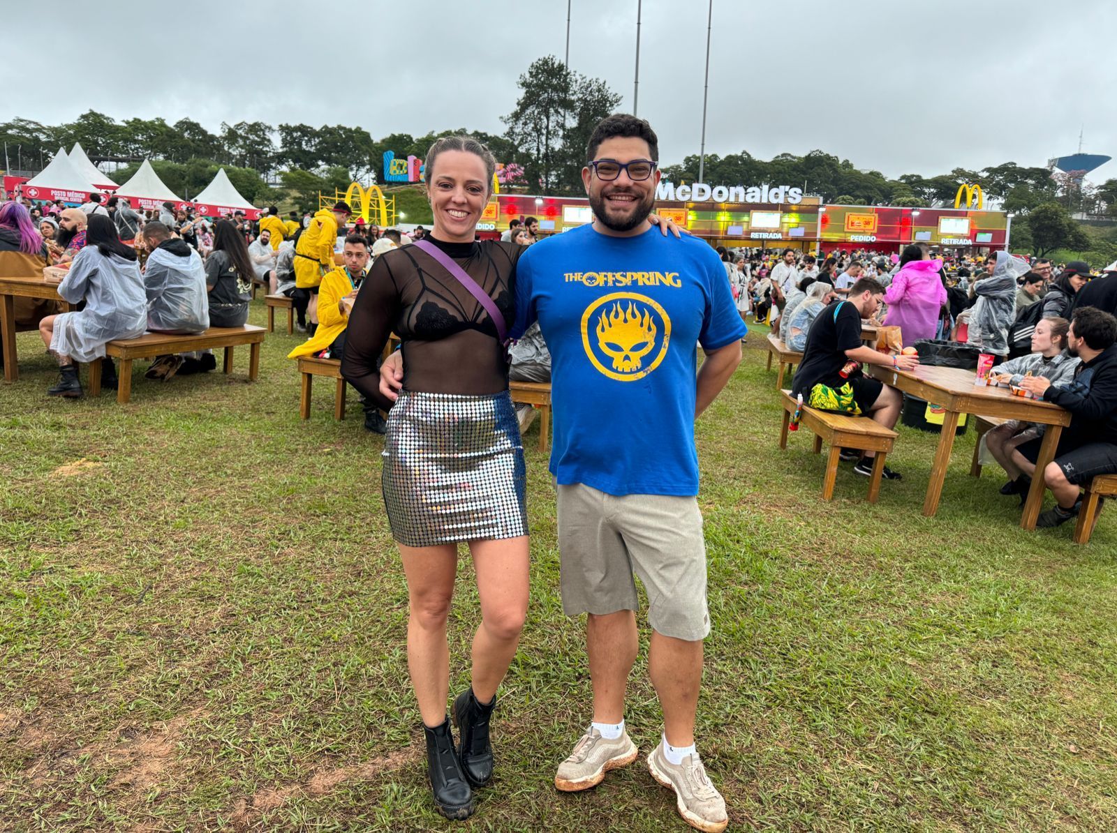 Flávia Bueno e Samuel Zeni com looks e camiseta de banda para curtir o Lolla / Nicoly Bastos/CNN