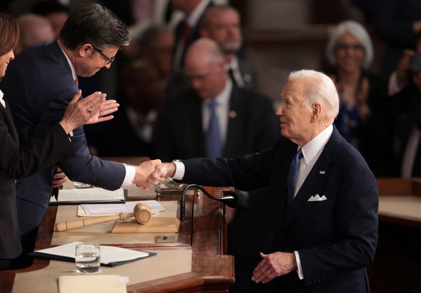 Joe Biden aperta a mão do presidente da Câmara, Mike Johnson, enquanto a vice-presidente Kamala Harris aplaude o discurso sobre o Estado da União / Win McNamee/Getty Images