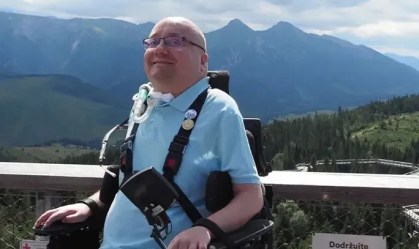 Homem de cadeira de rodas e respirador mecânico em frente a cenário de montanhas