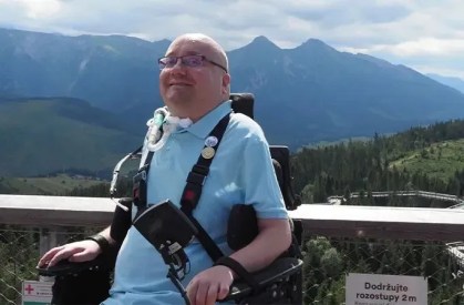 Homem de cadeira de rodas e respirador mecânico em frente a cenário de montanhas