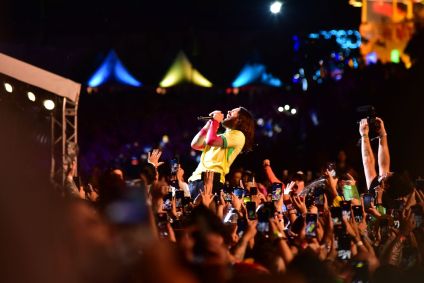 Vocalista no meio do público segurando microfone de olhos fechados