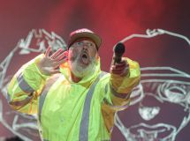 Vocalista do Limp Bizkit com uma mão na orelha e a outra segurando o microfone em direção ao público